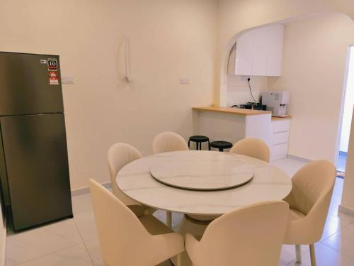 a kitchen with a table and chairs and a refrigerator at Area Indahpura or Taman Bersatu Kulai 3-4BR near AEON Airport JPO in Kulai