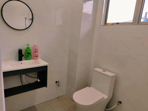 a bathroom with a toilet and a sink and a mirror at Area Indahpura or Taman Bersatu Kulai 3-4BR near AEON Airport JPO in Kulai