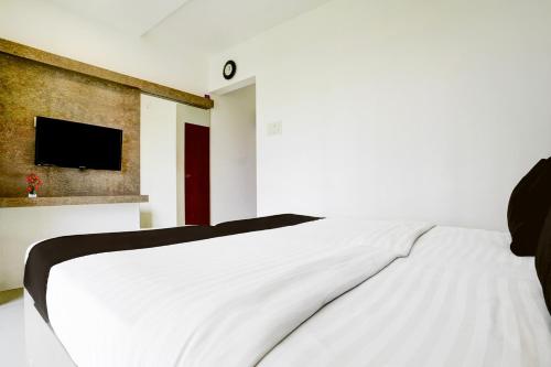 a bedroom with a white bed with a tv on the wall at Collection O Viviana Mall Thane West Formerly Athithi Stays in Thane