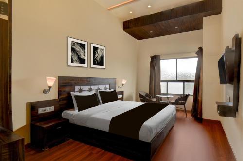 a hotel room with a large bed and a desk at Super Townhouse Oak Sinhgad Road Crossway Formerly Popular Hotel in Pune
