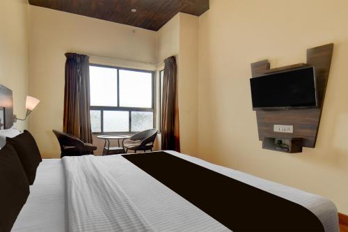 a hotel room with a bed and a flat screen tv at Super Townhouse Oak Sinhgad Road Crossway Formerly Popular Hotel in Pune