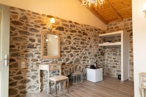 a stone wall in a room with a mirror and a stool at Kanalia Suites in Kanália