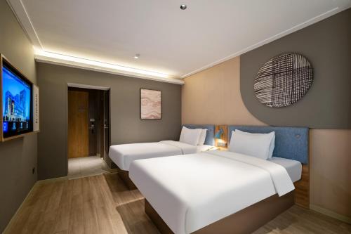a hotel room with two beds and a tv at Motel Xiamen Railway Station in Xiamen