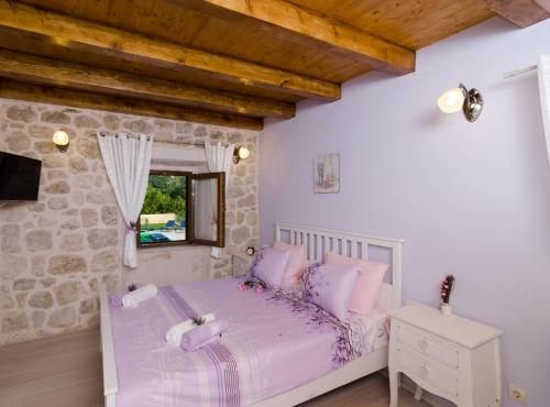 a bedroom with a bed and a stone wall at Villa Falcon Rook in Gruda