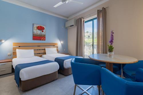 a hotel room with two beds and a table and chairs at Xemxija Bay Hotel in St Paul's Bay