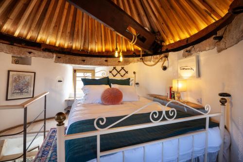 a bedroom with a bed with a wooden ceiling at The Indigo Windmill Retreat in Lourinhã