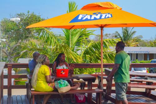 a group of people sitting at a picnic table under an umbrella at Ponta View Hotel in Ponta do Ouro