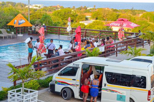 a group of people standing around a van next to a pool at Ponta View Hotel in Ponta do Ouro