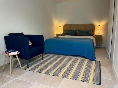 a bedroom with a blue bed and a blue chair at Studio neuf dans un écrin de verdure in Charbonnières-les-Bains