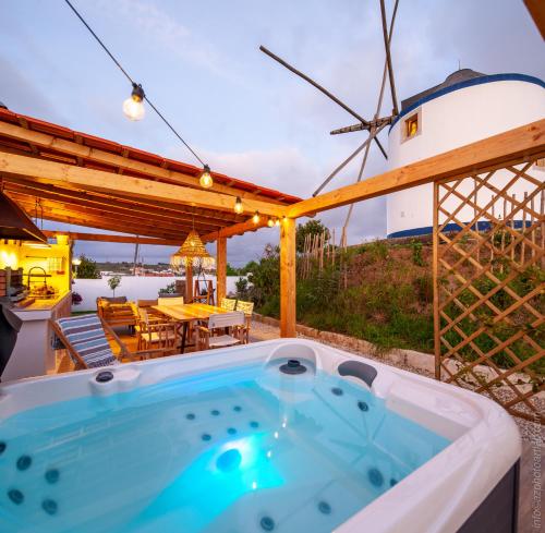 a hot tub on a patio with a windmill at The Indigo Windmill Retreat in Lourinhã