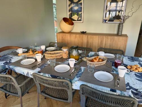 a table with a blue table cloth and chairs with food on it at Villa Georgia in Bénerville-sur-Mer