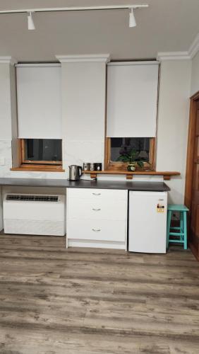 a kitchen with white cabinets and a wooden floor at Castle Studio Apartment in Dunedin