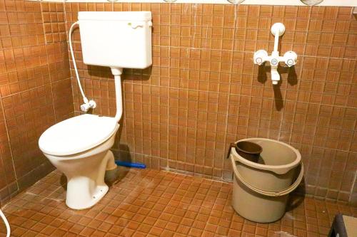 a bathroom with a toilet and a trash can at Lakeside Room stay in Yelagiri