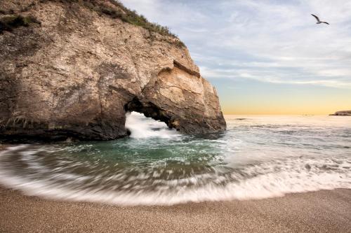 an arch in a rock in the water on a beach at Inn at the Cove in Pismo Beach