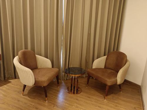 two chairs and a table in a room with curtains at The Maharaja Crest in Srinagar