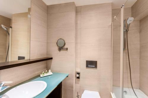 a bathroom with a sink and a shower at NH Brussels Stéphanie in Brussels
