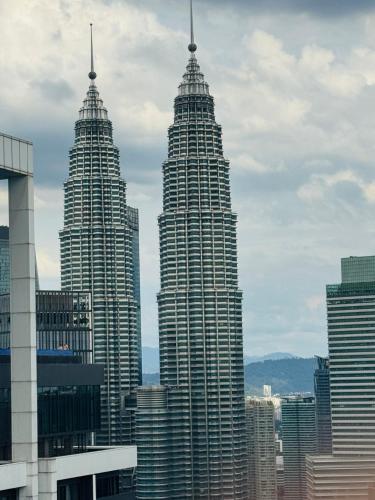 two tall skyscrapers in a city with buildings at THE PLATINUM KLCC by COZY STAY in Kuala Lumpur