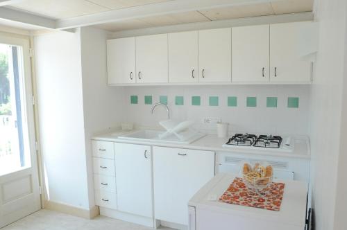 a white kitchen with white cabinets and a sink at Villa Rosato in Selva di Fasano