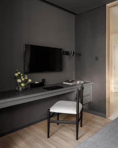 a desk with a chair and a television on a wall at Express by M Village Nguyễn Bỉnh Khiêm in Ho Chi Minh City