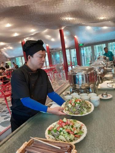 Sóc SơnにあるFifth Season Retreatのカウンターでピザ2枚を用意している男性