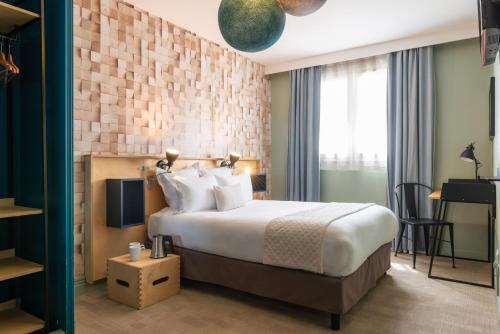 a hotel room with a bed and a tv at Hotel Bootcamp in Issy-les-Moulineaux