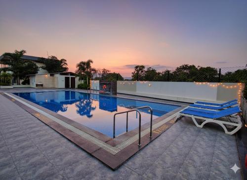 a swimming pool with two blue lounge chairs on a house at Lion Signature Family Resort in Sasan Gir
