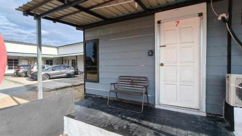 a bench sitting outside of a house with a white door at Aleesa Roomstay & Hotel in Pasir Puteh