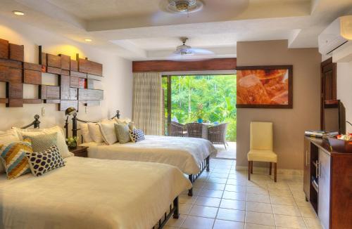 a hotel room with two beds and a window at Pumilio Mountain & Ocean Hotel in Jacó