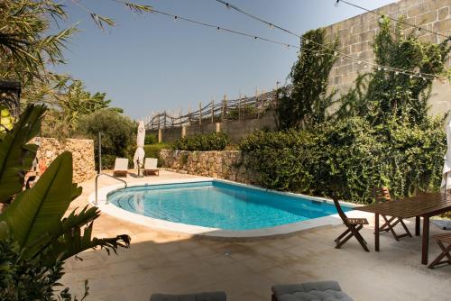 a swimming pool in a backyard with a table and chairs at Farmhouse Razzett Cora in Victoria
