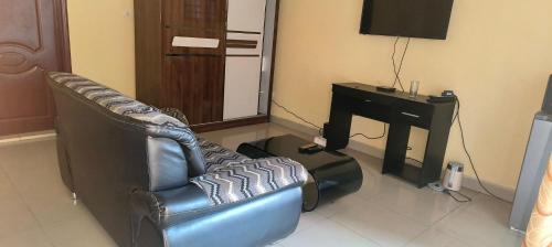 a living room with a couch and a desk and a television at Serene 5-Bedroom Apartment in Kinshasas 10me Rue Limete-Rsidentiel in Lemba-Gaba