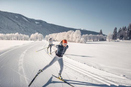two people are skiing down a snow covered slope at Hotel Tyrol in Malles Venosta