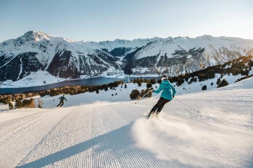 two people are skiing down a snow covered mountain at Hotel Tyrol in Malles Venosta