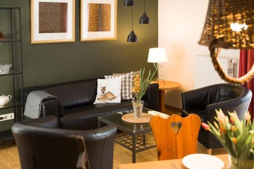 a living room with a black couch and chairs at Apparthotel Bad Schandau by STEIGER Hotels in Bad Schandau