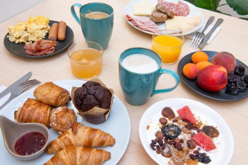 a table topped with plates of breakfast foods and drinks at Hotel Bootcamp in Issy-les-Moulineaux