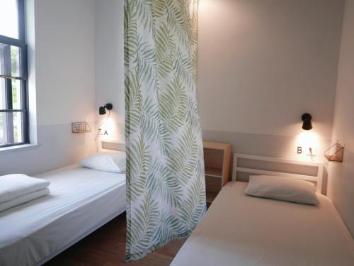 two beds in a room with a curtain between them at Shenzhen Loft Youth Hostel in Shenzhen