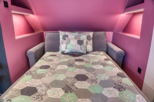 a small room with a bed in a pink room at MátraForRest in Mátraszentistván