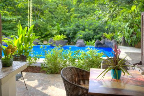 a patio with a table and chairs with plants at Pumilio Mountain & Ocean Hotel in Jacó