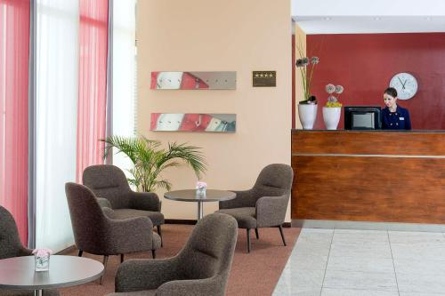 a waiting room with chairs and tables and a man at NH München Ost Conference Center in Munich