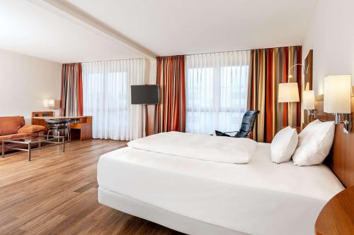 a hotel room with a white bed and a desk at NH München Ost Conference Center in Munich
