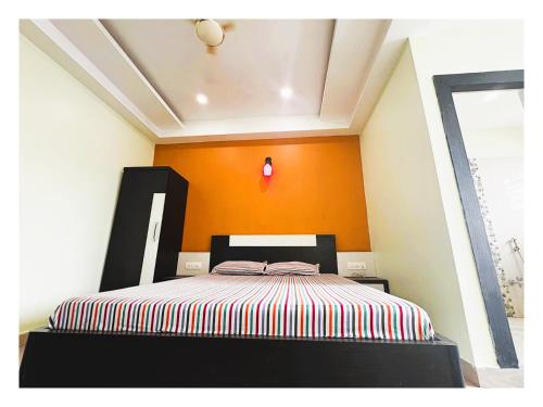 a bedroom with a bed with an orange wall at Pride Pitu পিটু Near The Amrabati Park AC OR NON AC Both Facility in Digha