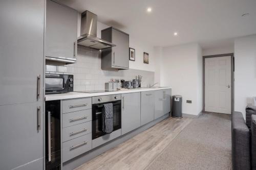 a kitchen with stainless steel appliances and white cabinets at Leeds 2-Bed Flat by Brookland Stays Serviced Short Lets with Free WiFi in Yeadon