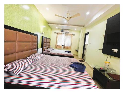 a bedroom with two beds and a flat screen tv at Pride Pitu পিটু Near The Amrabati Park AC OR NON AC Both Facility in Digha