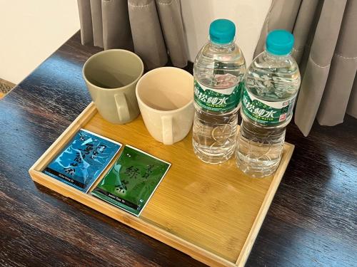 two bottles of water and two cups on a table at 有某行旅 yóu mǒu hostel in Tainan