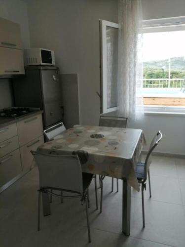 a table and chairs in a kitchen with a window at Apartment in Primosten with sea view, balcony, air conditioning, WiFi 5155-1 in Primošten