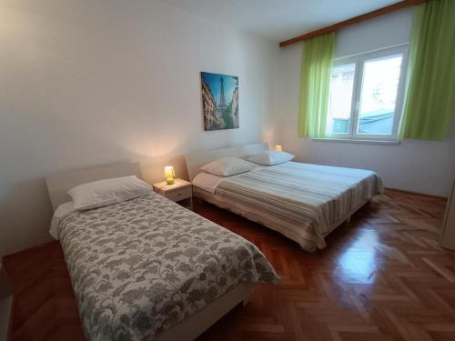a bedroom with two beds and a window and two lamps at Apartment in Primosten with sea view, balcony, air conditioning, WiFi 5155-1 in Primošten