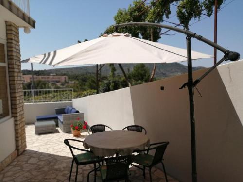 a table and chairs under an umbrella on a patio at Apartment in Primosten with sea view, balcony, air conditioning, WiFi 5155-1 in Primošten