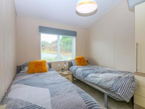 two beds in a room with a window at The Hideaway in Afon Wen Junction