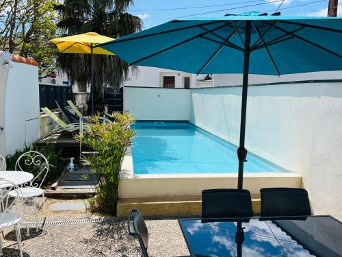 a blue umbrella sitting next to a swimming pool at Maison piscine centre ville La Tranche-sur-Mer in La Tranche-sur-Mer