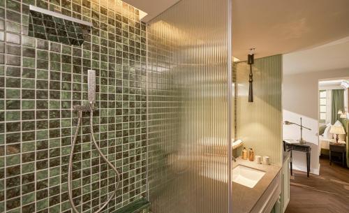 a bathroom with a glass shower with a sink at President Maison Signature By M Village in Ho Chi Minh City