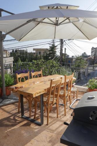 a wooden table and chairs under an umbrella at Beyt El Midan in Ehden